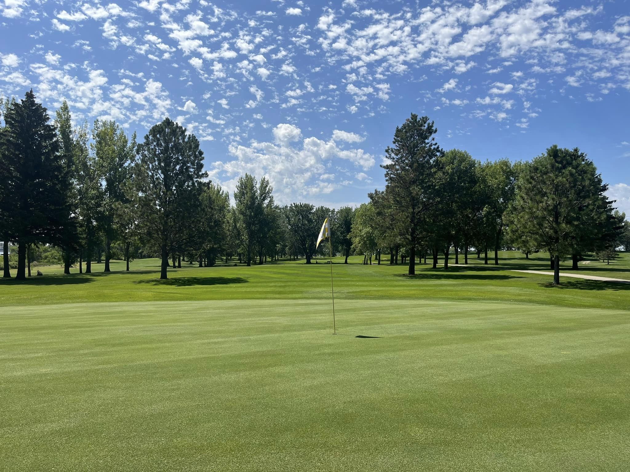 View of golf course green with clouds in the sky
